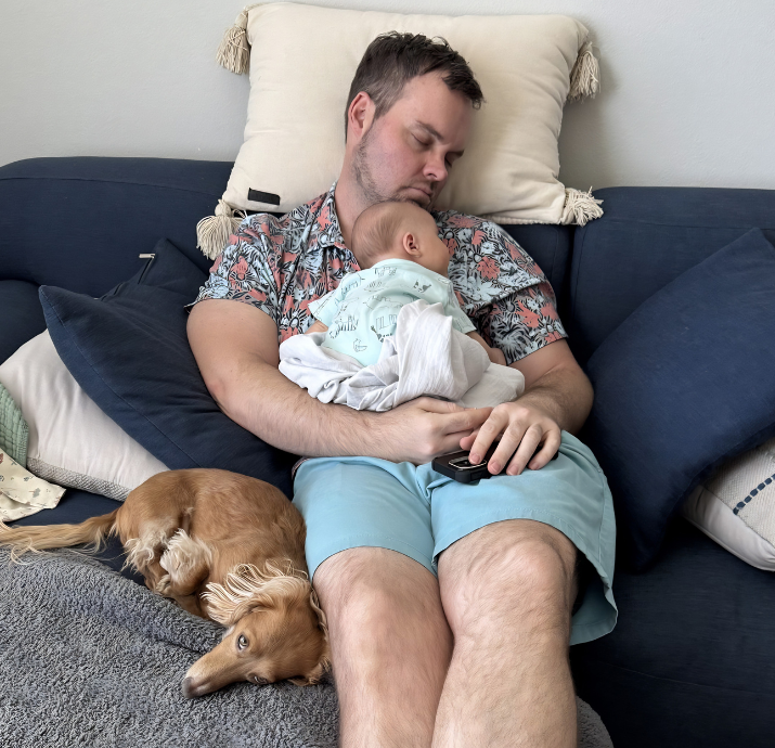 A tired dad resting with his newborn son.